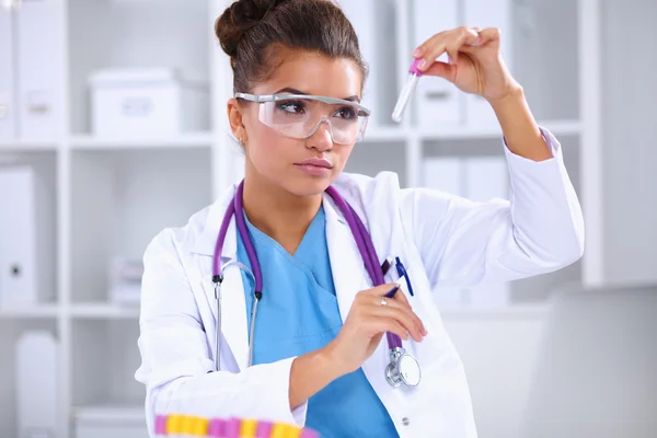 Woman researcher is surrounded by medical vials and flasks, isolated on white background — Stock Photo, Image