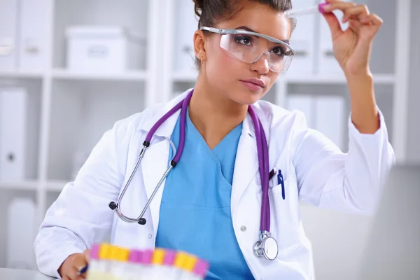 Woman researcher is surrounded by medical vials and flasks, isolated on white background — Stock Photo, Image