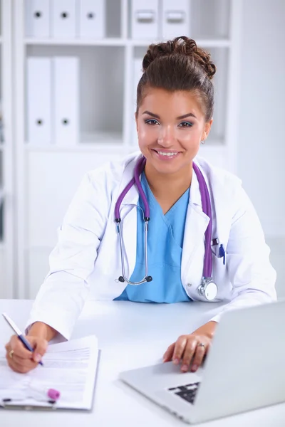 Female doctor sitting on the desk and working a laptop in hospital — Stock Photo, Image