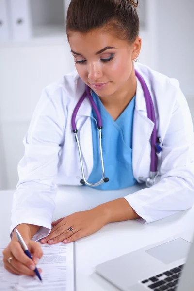 Female doctor sitting on the desk and working a laptop in hospital — Stock Photo, Image