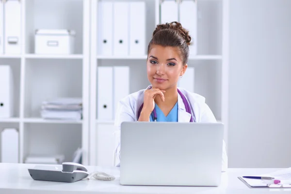 Female doctor sitting on the desk and working a laptop in hospital — Stock Photo, Image