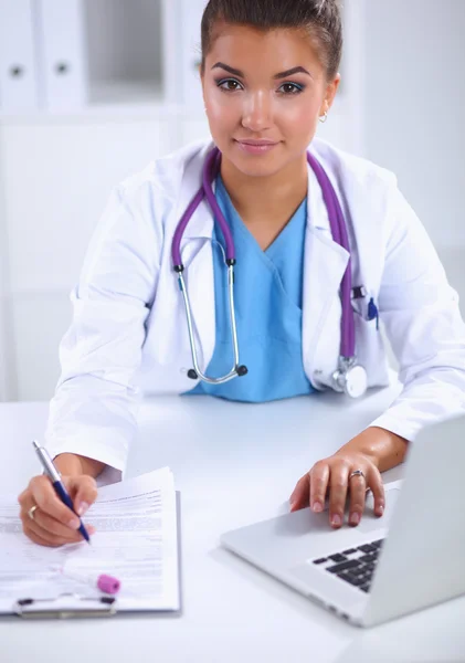 Female doctor sitting on the desk and working a laptop in hospital — Stock Photo, Image