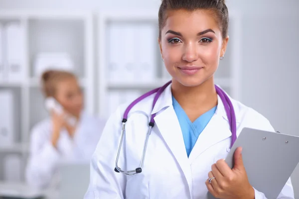 Lächelnde Ärztin mit Ordner in Uniform steht im Krankenhaus — Stockfoto