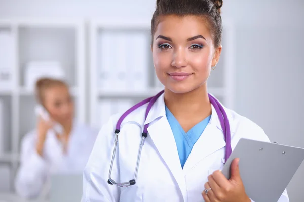 Smilende kvinnelig lege med en mappe i uniform stående på sykehuset – stockfoto
