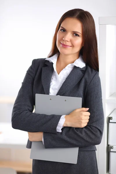 Attrayant jeune femme d'affaires debout près du bureau avec dossier dans le bureau — Photo