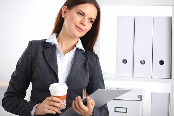 Привлекательная молодая деловая женщина, стоящая возле стола с папкой в офисе — стоковое фото