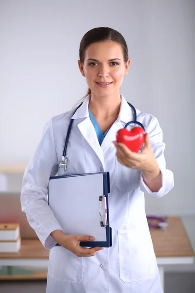 Jonge vrouw arts met map en een rood hart, geïsoleerd op witte achtergrond — Stockfoto