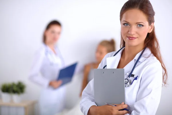 Médecin souriante avec un dossier en uniforme debout à l'hôpital — Photo