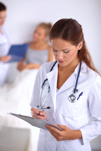 Smiling female doctor with a folder in uniform standing at hospital — Stock Photo, Image