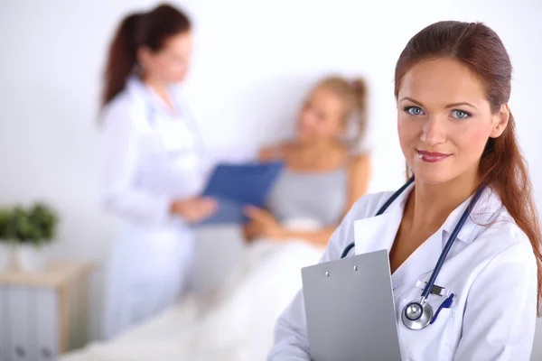 Médico sonriente con una carpeta en uniforme de pie en el hospital — Foto de Stock