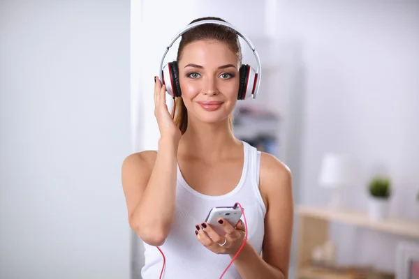 Mulher com fone de ouvido ouvindo música de pé em casa — Fotografia de Stock