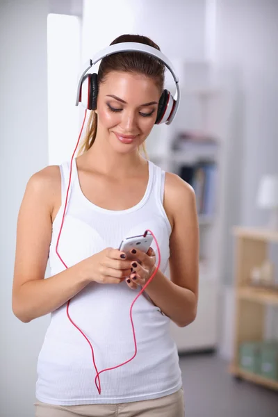 Femme avec casque écoutant de la musique debout à la maison — Photo