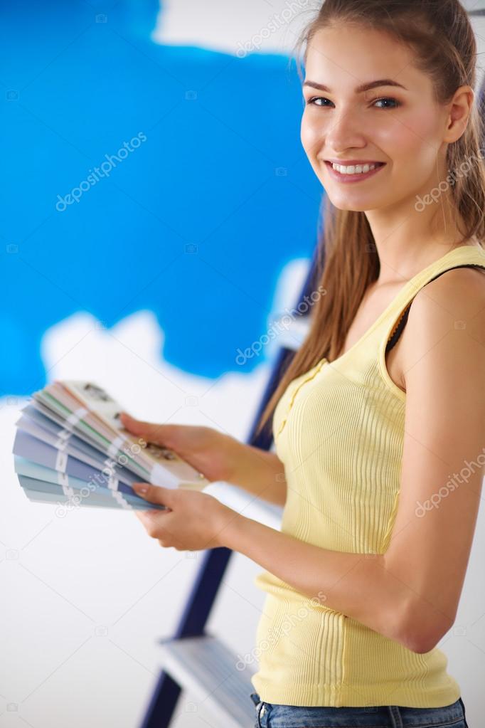 Young beautiful woman holding color palette , standing near wall.