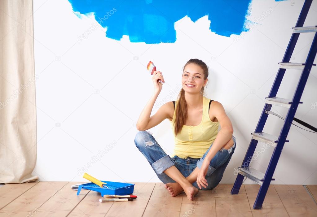 Portrait of female painter sitting on floor near wall after painting.