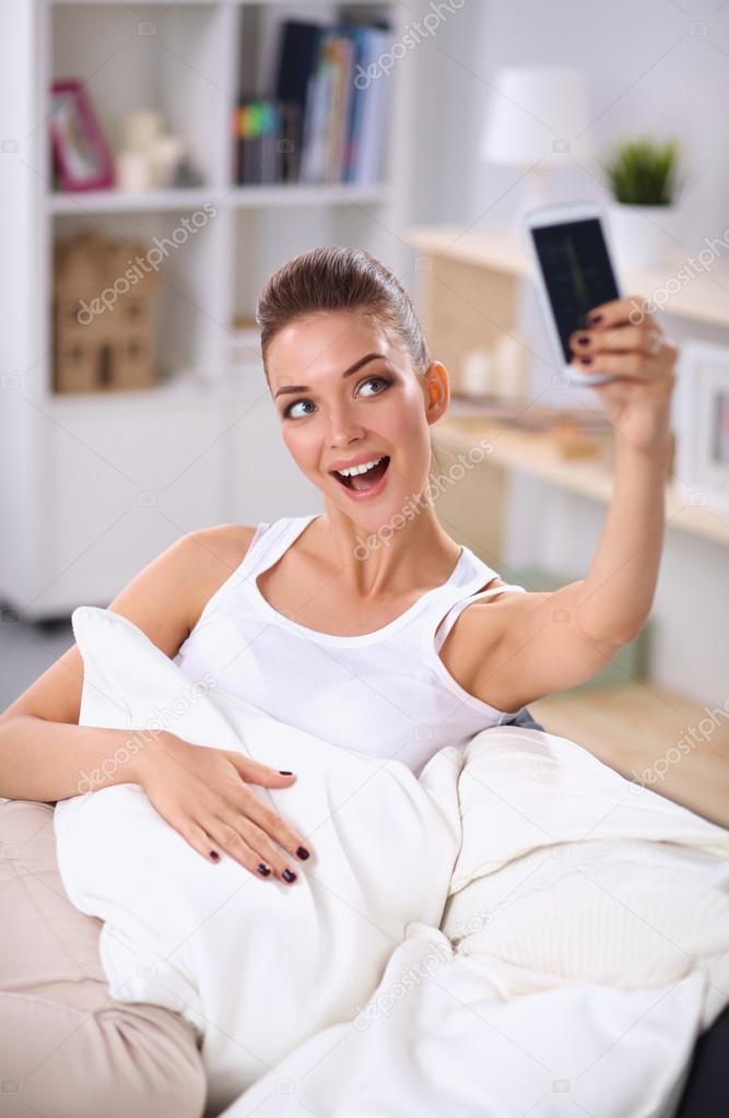 Happy brunette taking a photo of herself with her mobile phone in  bedroom