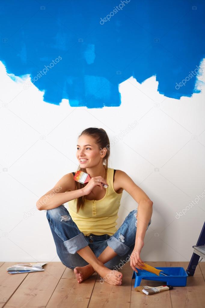 Portrait of female painter sitting on floor near wall after painting.