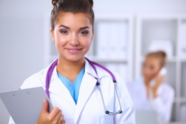 Gülümseyen kadın doktor, üniformalı bir klasörle Hostp 'ta bekliyor.