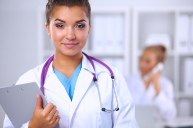 Gülümseyen kadın doktor, üniformalı bir klasörle Hostp 'ta bekliyor.