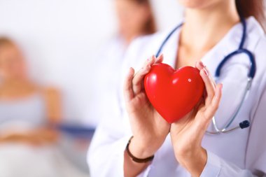 Beyaz backg izole kırmızı bir kalp tutan genç bir kadın doktor