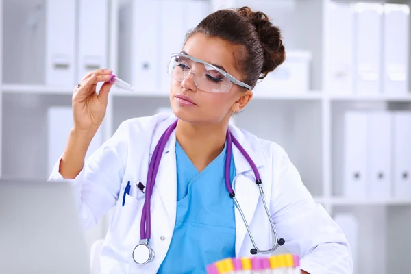 Woman researcher is surrounded by medical vials and flasks, iso — Stock Photo, Image