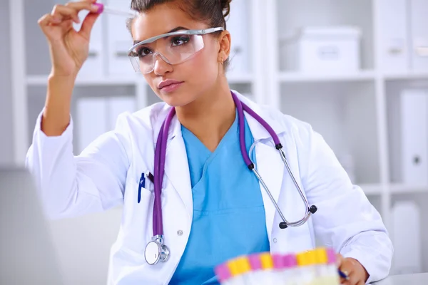 Woman researcher is surrounded by medical vials and flasks, iso — Stock Photo, Image