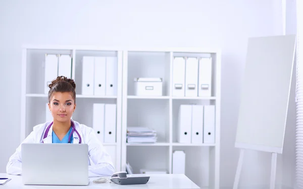 Female doctor sitting on the desk and working a laptop in hospi — Stock Photo, Image