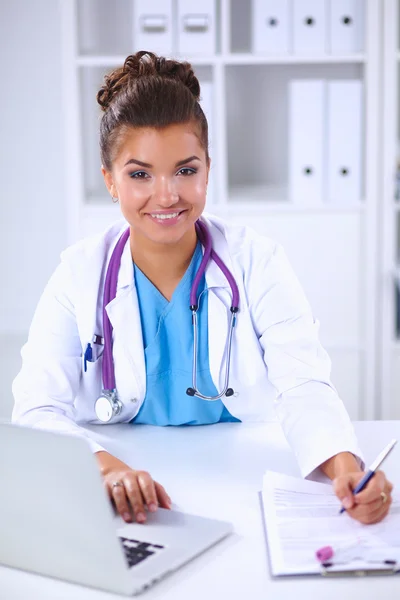 Vrouwelijke arts zit op het bureau en werkt een laptop in het ziekenhuis — Stockfoto