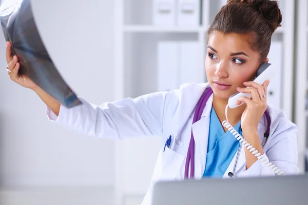 Γυναίκα γιατρό ψάχνει ακτινογραφία σάρωσης και να μιλάτε στο τηλέφωνο στο diagno — Φωτογραφία Αρχείου