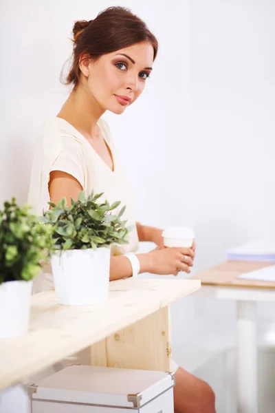 Aantrekkelijke jonge zakenvrouw staat in de buurt van een bureau in het kantoor — Stockfoto