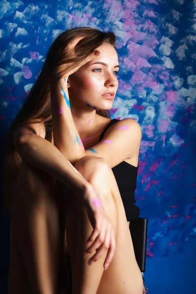 Young woman sitting near painting wall — Stock Photo, Image