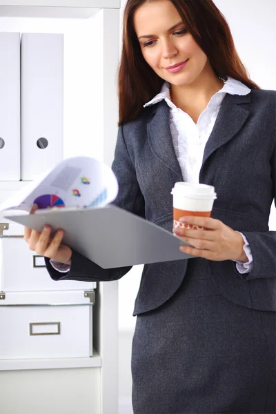 Atractiva joven mujer de negocios de pie cerca de escritorio con carpeta i — Foto de Stock