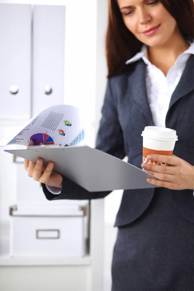 Attractive young businesswoman standing near desk with folder i — Stock Photo, Image