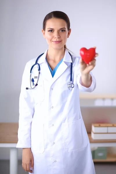 Mujer joven doctora sosteniendo un corazón rojo, aislado en el respaldo blanco — Foto de Stock