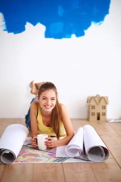 Mujer joven acostada en el suelo y mirando el plano de la nueva — Foto de Stock