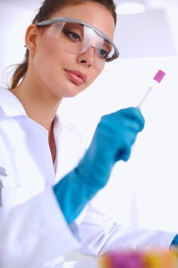 Kadın araştırmacının etrafı ilaç şişeleri ve mataralarla çevrili.