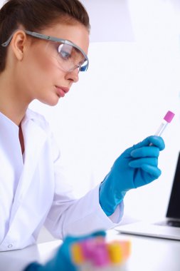 Kadın araştırmacının etrafı ilaç şişeleri ve mataralarla çevrili.