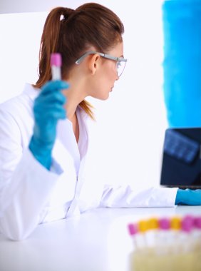 Kadın araştırmacının etrafı ilaç şişeleri ve mataralarla çevrili.