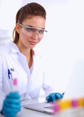 Kadın araştırmacının etrafı ilaç şişeleri ve mataralarla çevrili.