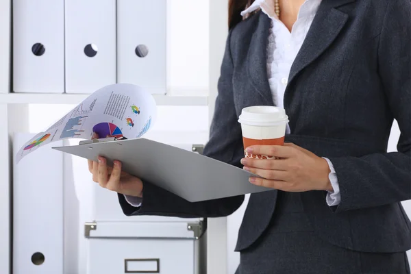 Zakenvrouw met mappen en kopje koffie, permanent in kantoor — Stockfoto