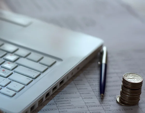 Mynt och pennan nära laptop — Stockfoto