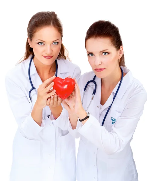 Duas mulheres médico segurando um coração vermelho, isolado em fundo branco — Fotografia de Stock