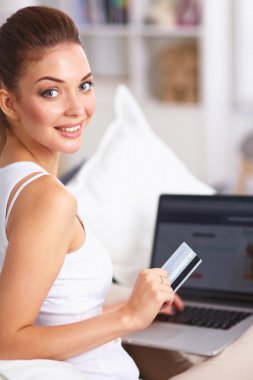 Kadın kredi kartı ve bilgisayarla online alışveriş yapıyor.