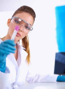 Kadın araştırmacı, beyaz arka planda izole edilmiş ilaç şişeleri ve mataralarla çevrili.