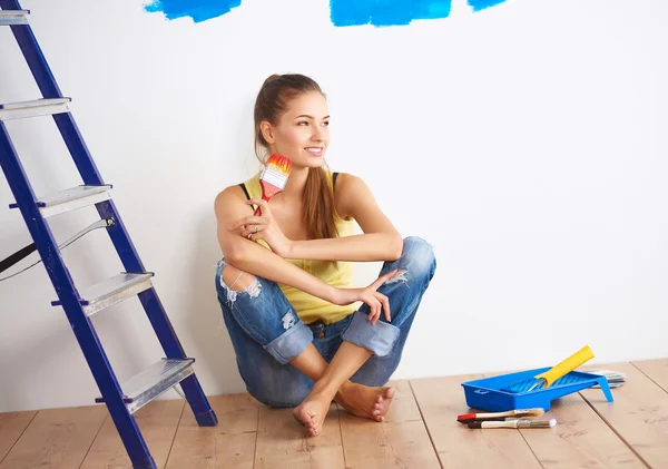 Portret van vrouwelijke schilder zittend op de vloer in de buurt van muur naar schilderij. — Stockfoto