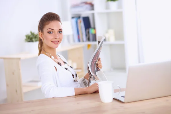 Söt affärskvinna hålla tidningen sitter vid hennes skrivbord i ljust kontor — Stockfoto