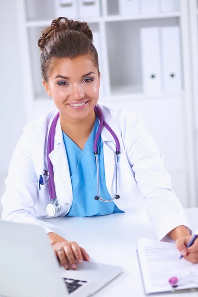 Female doctor sitting on the desk and working a laptop in hospital — Stock Photo, Image