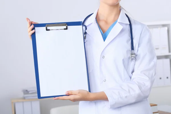 Médico sonriente con una carpeta en uniforme de pie en el hospital — Foto de Stock