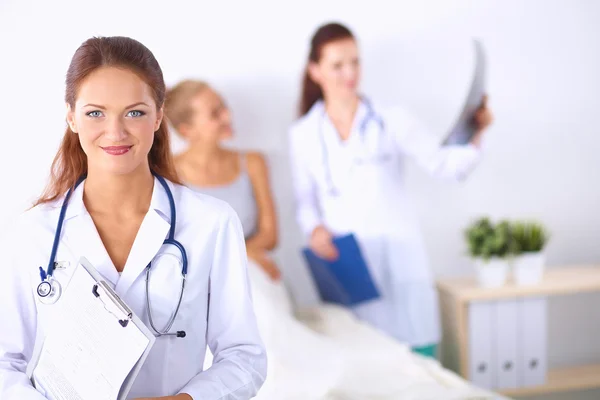 Médico sonriente con una carpeta en uniforme de pie en el hospital — Foto de Stock