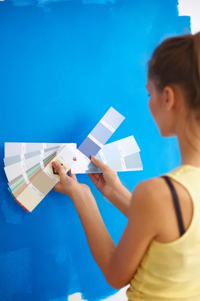 Mladá krásná žena drží paletu barev, stojí u zdi. — Stock fotografie