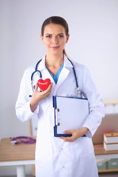 Jonge vrouw arts met map en een rood hart, geïsoleerd op witte achtergrond — Stockfoto